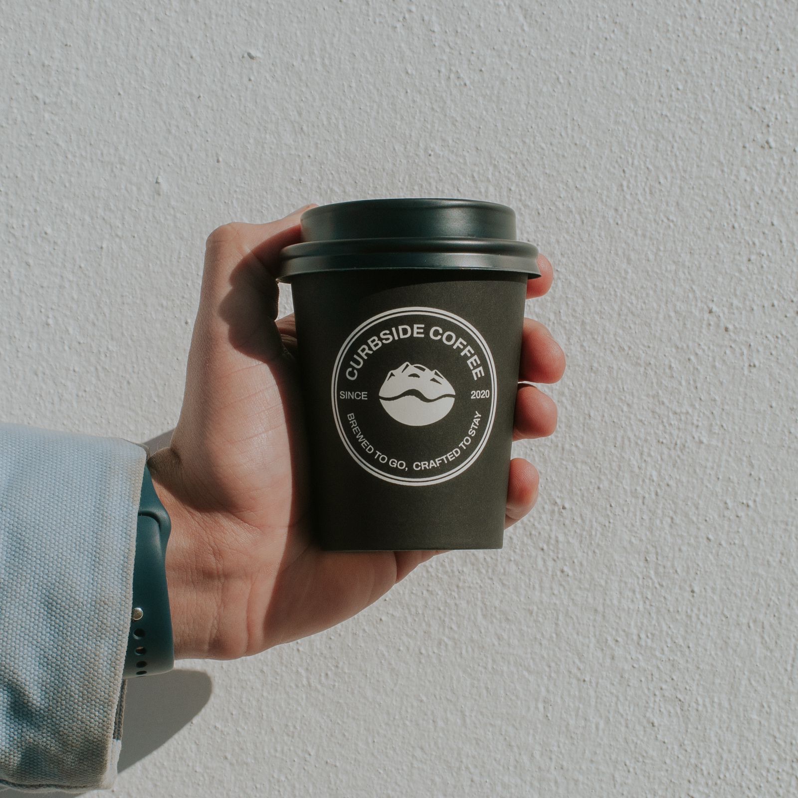 Hand holding a branded Curbside Coffee cup